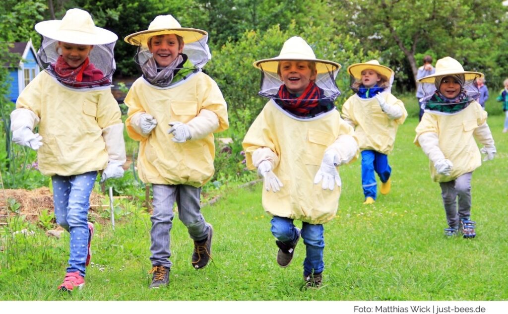 Bienen Erlebnis Tag, Kinder laufen auf einer Wiese in Bienenschutzanzügen