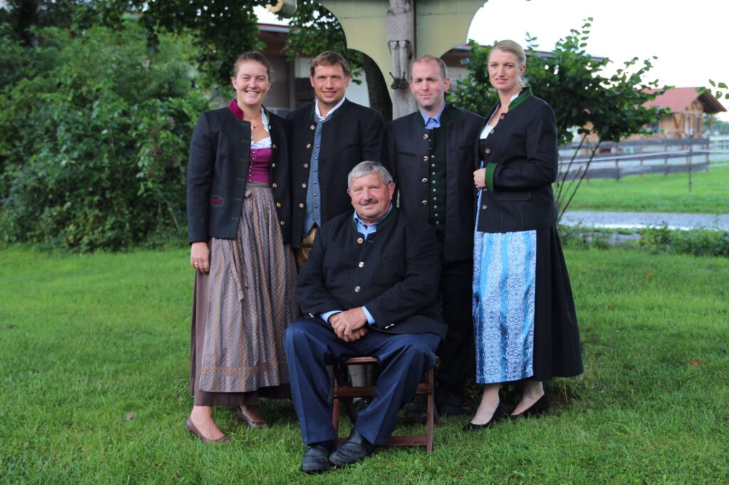 Familie Reitsberger steht auf einer Wiese und lächelt in die Kamera